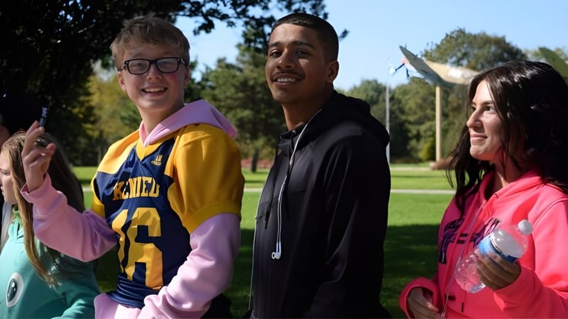 Drei Schülerinnen und Schüler stehen gemeinsam in einer parkähnlichen Umgebung auf dem Campus der Honourable W.C. Kennedy Collegiate.