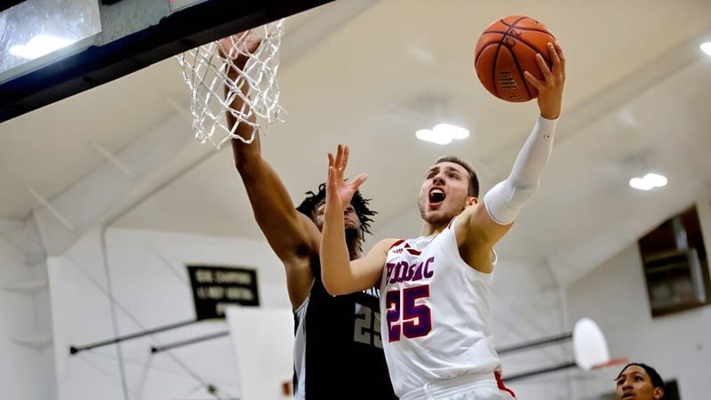 Ein Basketballspieler in weißem Trikot springt zu einem Wurf auf dem Basketballfeld der Hoosac School.