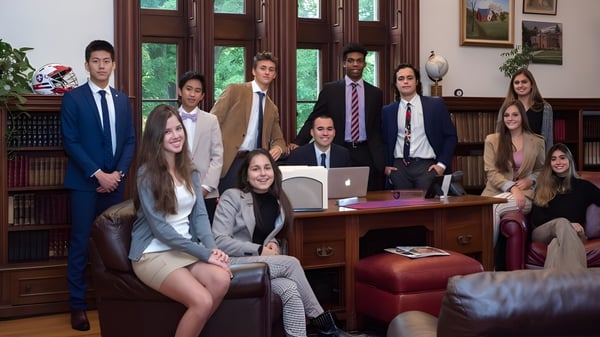 Eine Gruppe junger Fachkräfte arbeitet gemeinsam in einem holzvertäfelten Büro der Hoosac School.