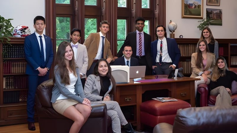 Eine Gruppe junger Fachkräfte arbeitet gemeinsam in einem holzvertäfelten Büro der Hoosac School.
