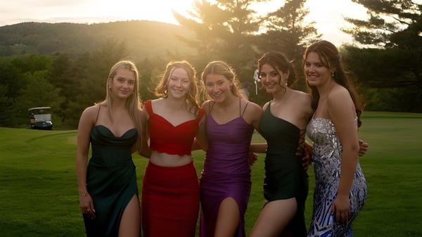 Fünf Schülerinnen der Hoosac School stehen auf einer Wiese vor bewaldeten Bergen bei Sonnenuntergang.