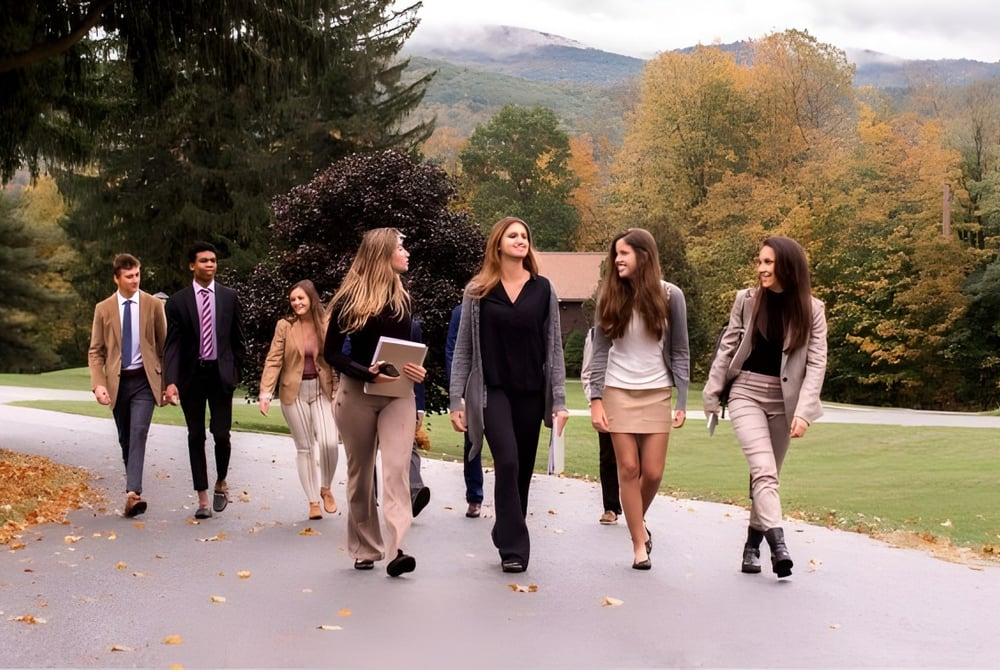 Eine Gruppe von Schülern der Hoosac School macht einen Spaziergang auf einem Weg mit herbstlichem Laub und Bergen im Hintergrund.