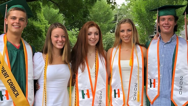 Fünf Schüler in Abschlusskleidung stehen gemeinsam im Grünen auf dem Campus der Hopkinton High School.