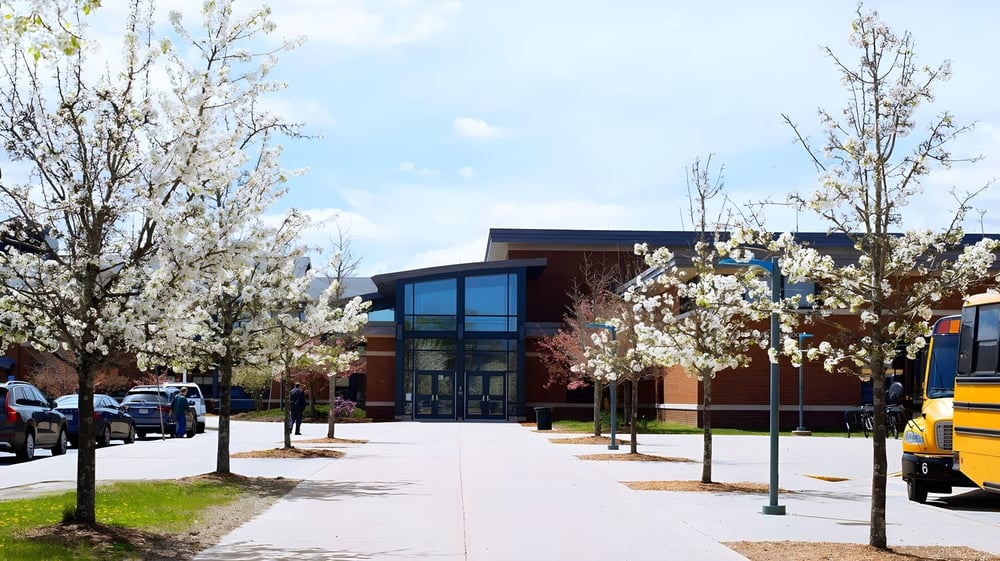 Das moderne Gebäude der Hopkinton High School mit großen Fenstern und blühenden Bäumen im Außenbereich.