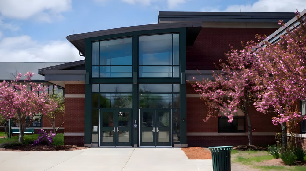 Das moderne Gebäude des Hopkinton Public School District mit rotem Backstein und blühenden Kirschbäumen im Vordergrund.