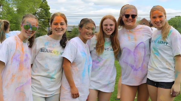 Eine Gruppe von Schülerinnen und Schülern der Hotchkiss School posiert draußen mit bunter Farbe bedeckt vor grünem Hintergrund.