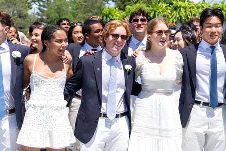 Eine Gruppe von Schülern der Hotchkiss School versammelt sich draußen vor Palmen und grüner Landschaft.