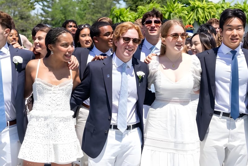 Eine Gruppe von Schülern der Hotchkiss School versammelt sich draußen vor Palmen und grüner Landschaft.