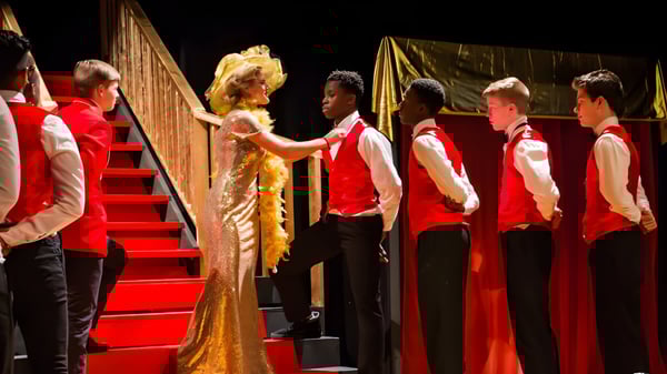 Eine Gruppe von Schülerinnen und Schülern der Houghton Academy trägt auf einer Bühne festliche Gewänder während einer Abschlussfeier.