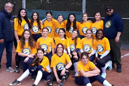 Eine Gruppe Schülerinnen der Howard S. Billings High School posiert zusammen auf dem Baseballfeld.