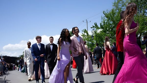 Schüler der Howard S. Billings High School in formeller Kleidung beim Gang auf einem von Grün umgebenen Weg.