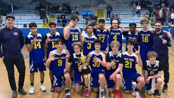 Eine Gruppe von Schülern der Howe Sound Secondary School posiert zusammen in einer Sportarena während eines Basketballspiels.