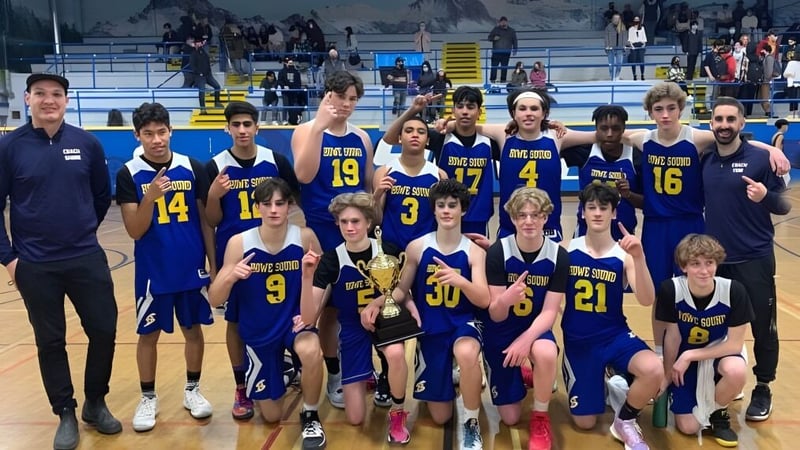 Eine Gruppe von Schülern der Howe Sound Secondary School posiert zusammen in einer Sportarena während eines Basketballspiels.
