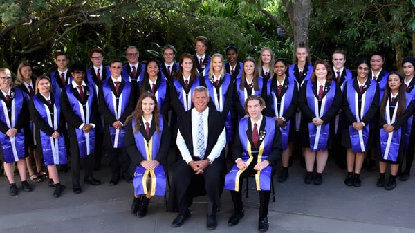 Eine Gruppe von Absolventinnen und Absolventen des Howick College steht gemeinsam in akademischer Kleidung im Grünen.