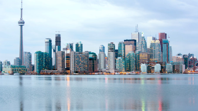 Ein beeindruckendes Stadtpanorama mit Wolkenkratzern und Hochhäusern spiegelt sich im ruhigen Wasser vor dem Hudson College.