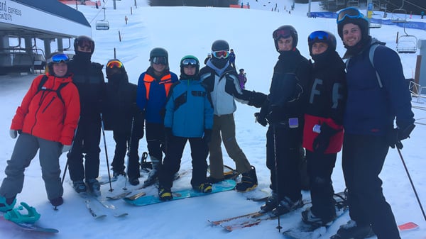 Eine Gruppe von Schülerinnen und Schülern der Hugh Boyd Secondary School steht mit Skiausrüstung auf einem verschneiten Hang.