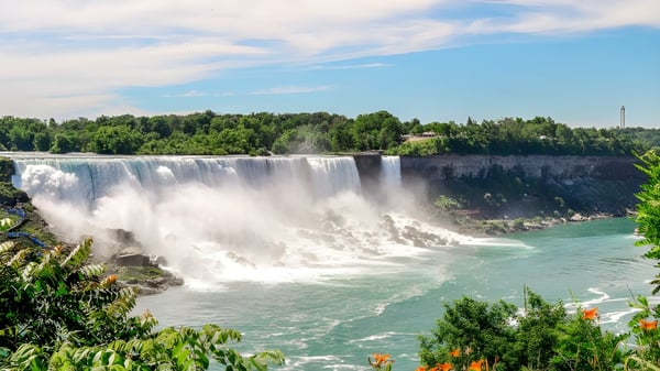 Ein Wasserfall fließt über eine Felsklippe, umgeben von grüner Vegetation, zu sehen nahe der École Secondaire Hugh McRoberts Secondary School.