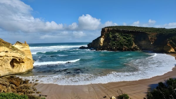 Eine malerische Küstenlandschaft mit Sandstrand und Klippen vor dem Hunters Hill High School Gebäude.