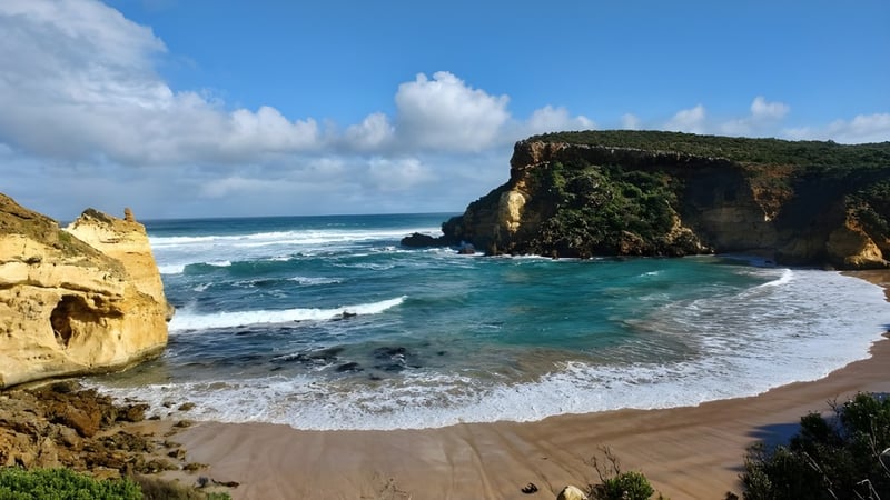Eine malerische Küstenlandschaft mit Sandstrand und Klippen vor dem Hunters Hill High School Gebäude.