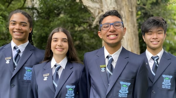 Vier Schülerinnen und Schüler der Hunters Hill High School stehen zusammen in einem natürlichen Umfeld mit Bäumen im Hintergrund.