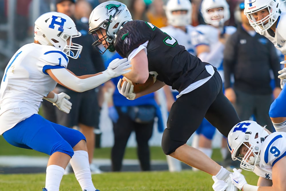 Zwei Spieler beim Football-Tackle auf dem Spielfeld der Hunting Hills High School vor Zuschauern.