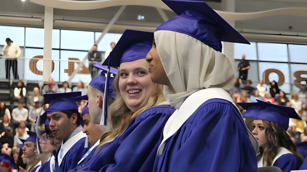 Eine Gruppe von Absolventinnen und Absolventen der Hunting Hills High School trägt lila Abschlussgewänder und Hüte in einem vollen Auditorium.