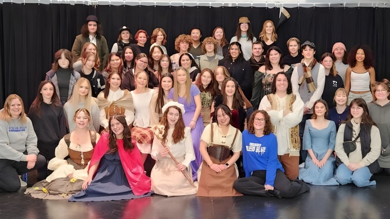 Eine große Gruppe Frauen steht gemeinsam auf der Bühne der Hunting Hills High School vor einem schwarzen Vorhang.