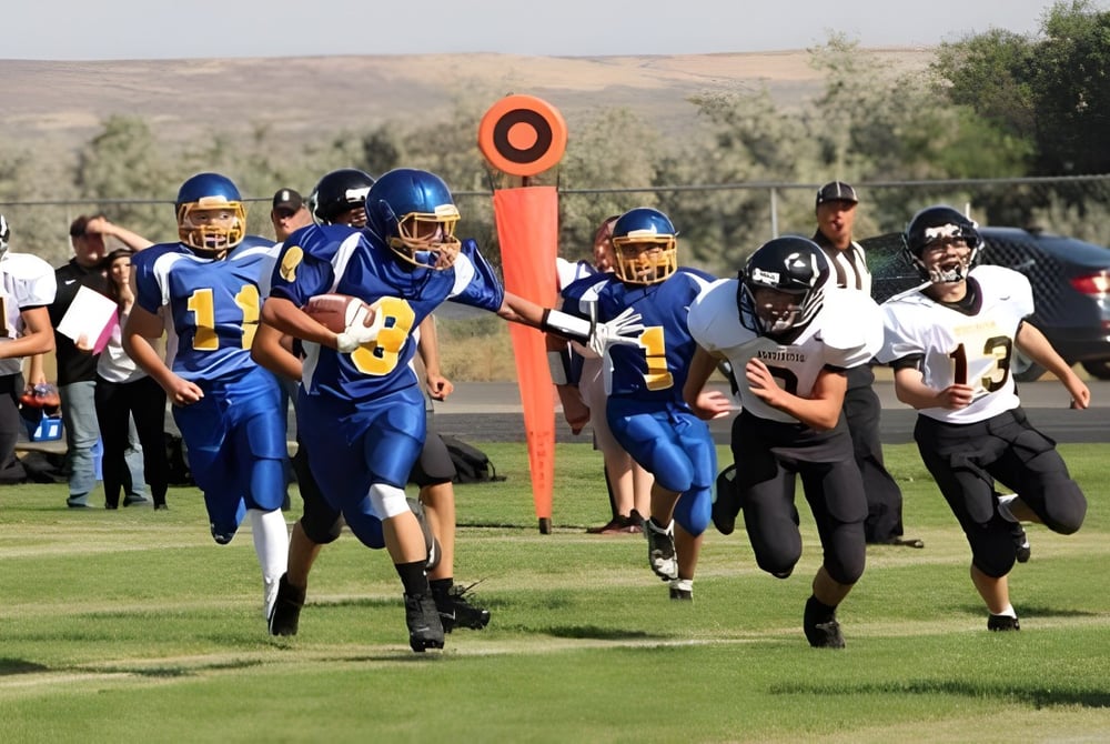 Eine Gruppe von Fußballspielern trainiert auf dem Sportplatz der Huntington High School vor einer hügeligen Landschaft.