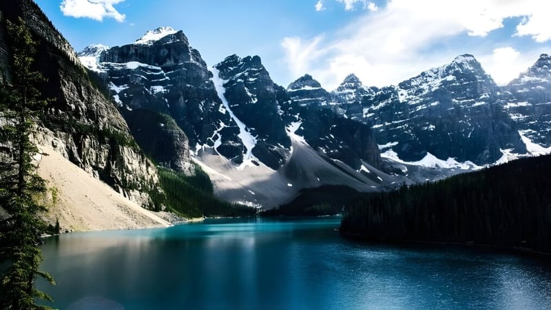 Ein türkisfarbener Bergsee umgeben von schneebedeckten Gipfeln und grüner Landschaft auf dem Gelände der Huntsville School.
