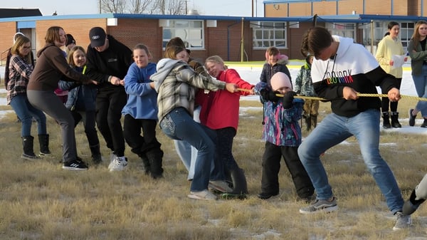 Schüler der Huntsville School nehmen an einer Teamaktivität im Freien auf einer Wiese neben einem Backsteingebäude teil.
