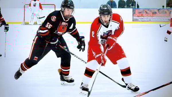 Zwei Hockeyspieler der Huron High School kämpfen in einem Spiel auf dem Eisfeld gegeneinander.
