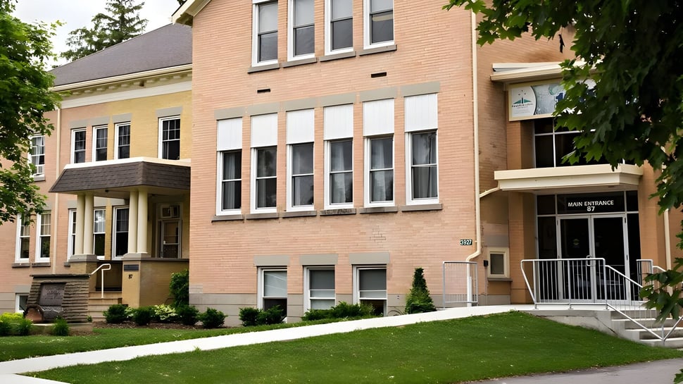 Das mehrstöckige Backsteingebäude des Huron-Perth Catholic District School Board ist von gepflegtem Rasen und Bäumen umgeben.