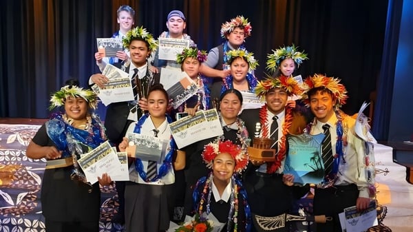 Eine Gruppe von Schülerinnen und Schülern der Hutt Valley High School steht mit bunten Kostümen und Auszeichnungen vor einem gemusterten Hintergrund.