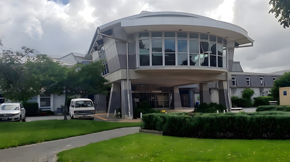 Das moderne Gebäude der Hutt Valley High School besitzt eine gewölbte Glasfassade und ein kuppelartiges Dach in einer gepflegten Grünfläche.