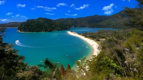 Ein tropischer Strand mit klarem türkisfarbenem Wasser und grünen Hügeln, aufgenommen in der Nähe von Hutt Valley High School.