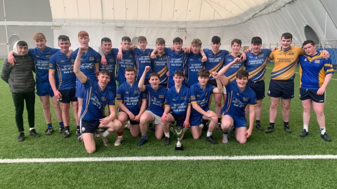 Eine Gruppe von Schülerinnen und Schülern des Iascaigh College posiert auf einem Fußballfeld vor einer großen aufblasbaren Struktur.