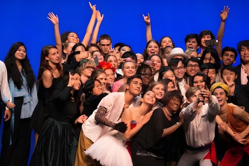 Schülerinnen und Schüler der Idyllwild Arts Academy feiern gemeinsam vor einem blauen Hintergrund.