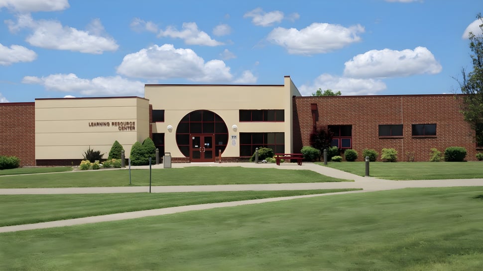 Das moderne Backsteingebäude der Illinois Eastern Community Colleges mit einem Bogen-Eingang auf gepflegtem Rasen und umgeben von grüner Vegetation.