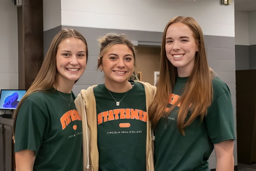 Drei lächelnde Schülerinnen stehen zusammen in einem Flur auf dem Campus der Illinois Eastern Community Colleges.