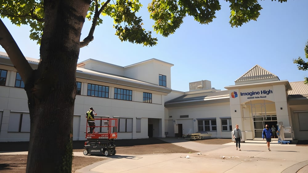 Ein modernes Schulgebäude der Imagine High Integrated Arts and Technology Secondary School mit einem Aufzug für Bauarbeiten im Vordergrund.