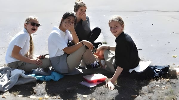 Eine Gruppe von Schülerinnen und Schülern der Immaculata Regional School sitzt am Strand und verbringt gemeinsam ihre Freizeit im Freien.