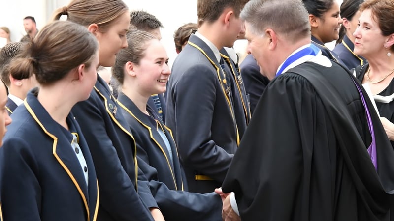 Eine Gruppe von Schülern in Abschlusskleidung steht gemeinsam bei einer feierlichen Veranstaltung am Immanuel College.