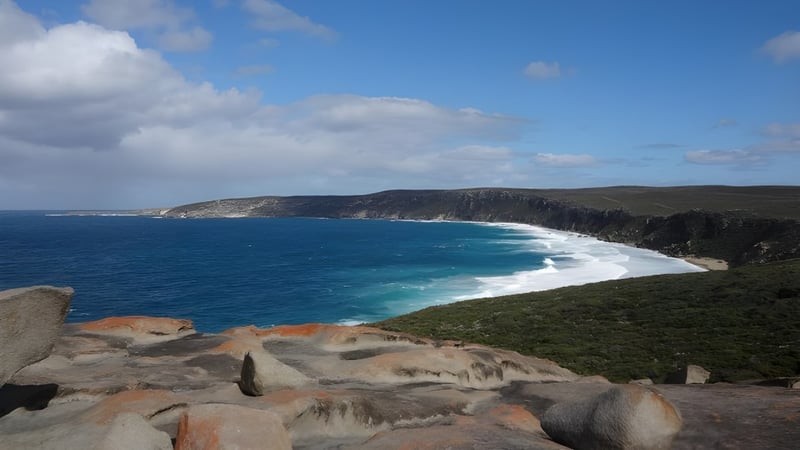 Eine felsige Küste mit Wellen und blauem Meer unter einem bewölkten Himmel in der Nähe des Immanuel College.
