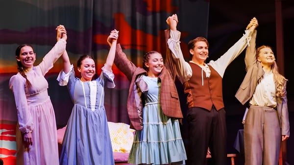 Fünf Frauen stehen auf der Bühne der Indian River Charter High School und heben ihre Arme in einer feierlichen Geste.