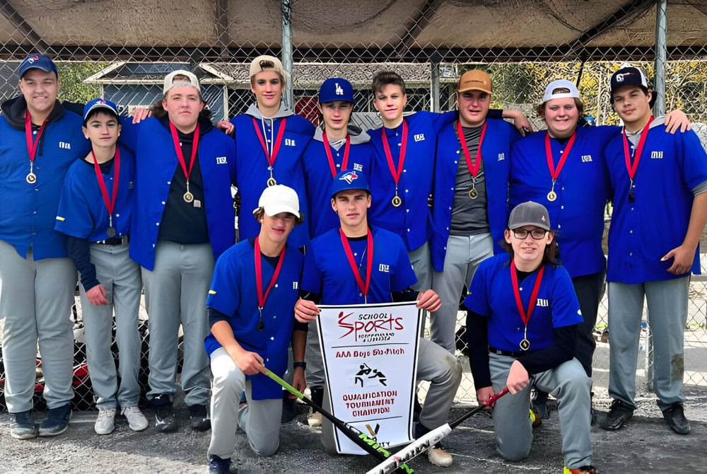 Schüler in blauen Uniformen mit Medaillen stehen gemeinsam vor dem eingezäunten Kids Sports Bereich der Indian River High.