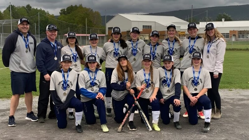 Eine Gruppe Schüler von Indian River High posiert als Sportteam draußen auf einem Feld vor einem Gebäude.