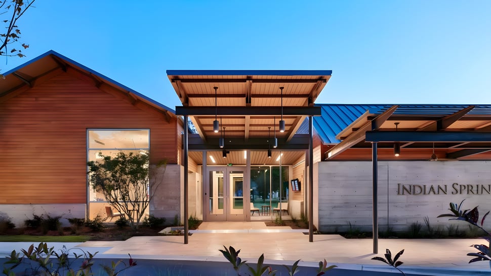 Das moderne Holzgebäude der Indian Springs School mit einem überdachten Eingangsbereich vor klarem Himmel.