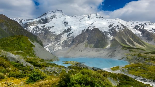 Eine idyllische Landschaft mit schneebedeckten Bergen und einem türkisfarbenen See vor grüner Vegetation in der Umgebung der Inglewood High School.
