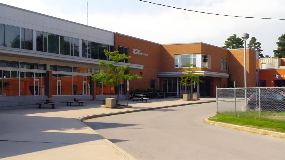 Das moderne mehrstöckige Gebäude der Innisdale Secondary School mit Glaswänden und orangen sowie grauen Fassadenelementen.