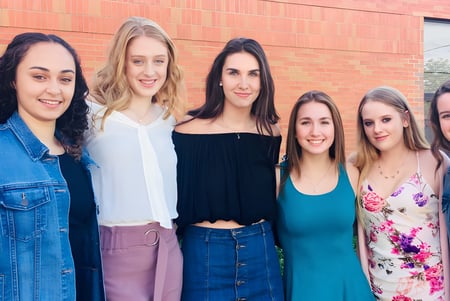 Eine Gruppe von sechs jungen Schülerinnen steht vor einer Backsteinmauer auf dem Gelände der Innisdale Secondary School.